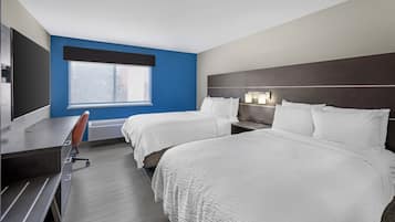 A hotel room with two beds, a desk, and a window.