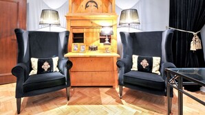 A room with two black armchairs, a wooden cabinet with glass jars, and two lamps. - Hotel Sir & Lady Astor (Düsseldorf)