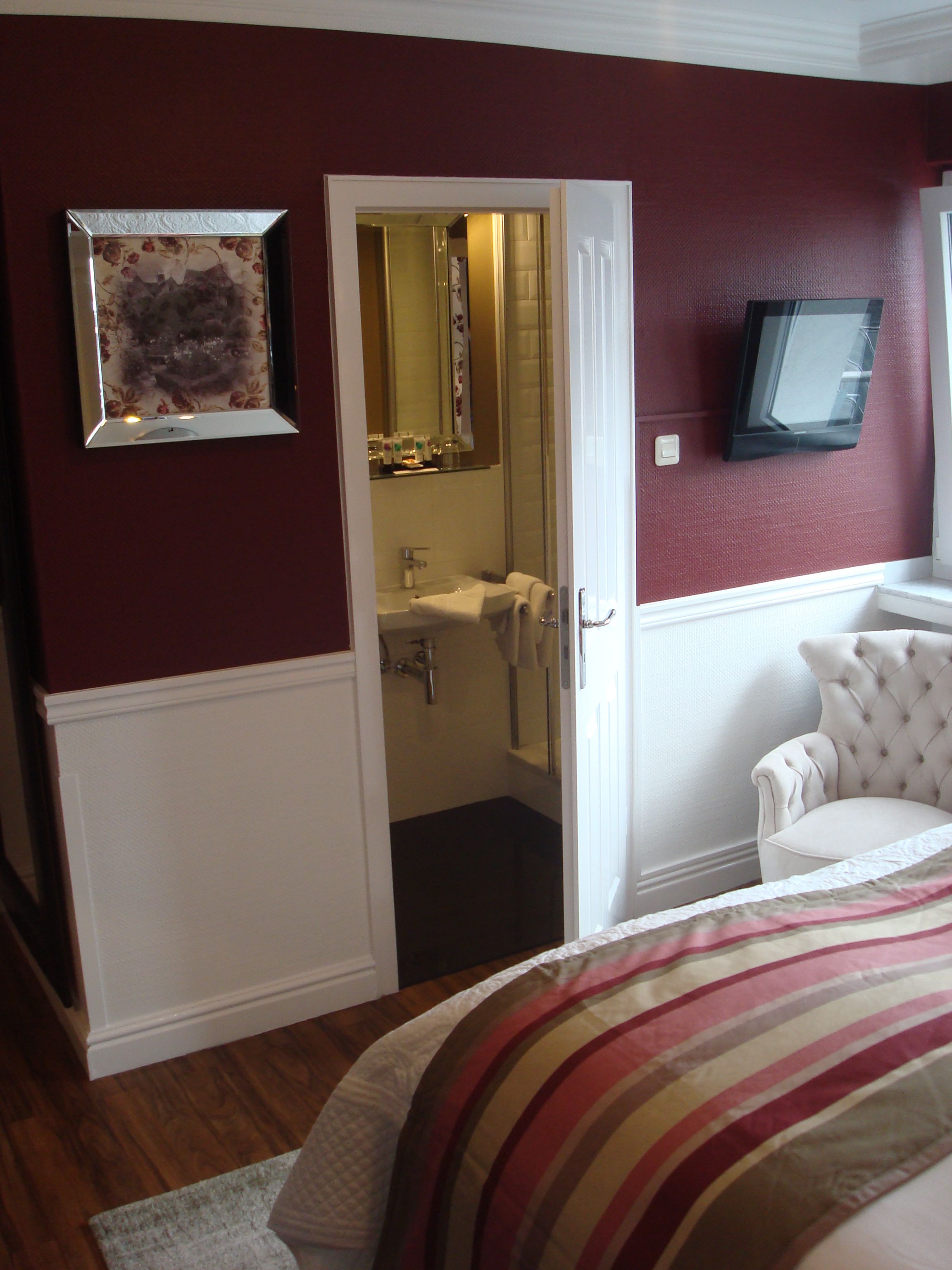 Una camera da letto con un letto, una sedia, un ingresso che conduce al bagno e un quadro appeso alla parete.