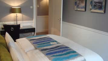 Een hotelkamer met een bed, een bureau, een lamp en een deur naar een badkamer.