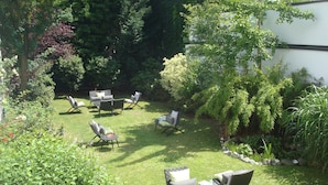 A garden with a lawn, outdoor furniture, and various plants. - Hotel Sir & Lady Astor (Düsseldorf)