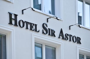Segnaletica di un hotel con il nome 'Hotel Sir Astor' in caratteri grandi e in grassetto.
