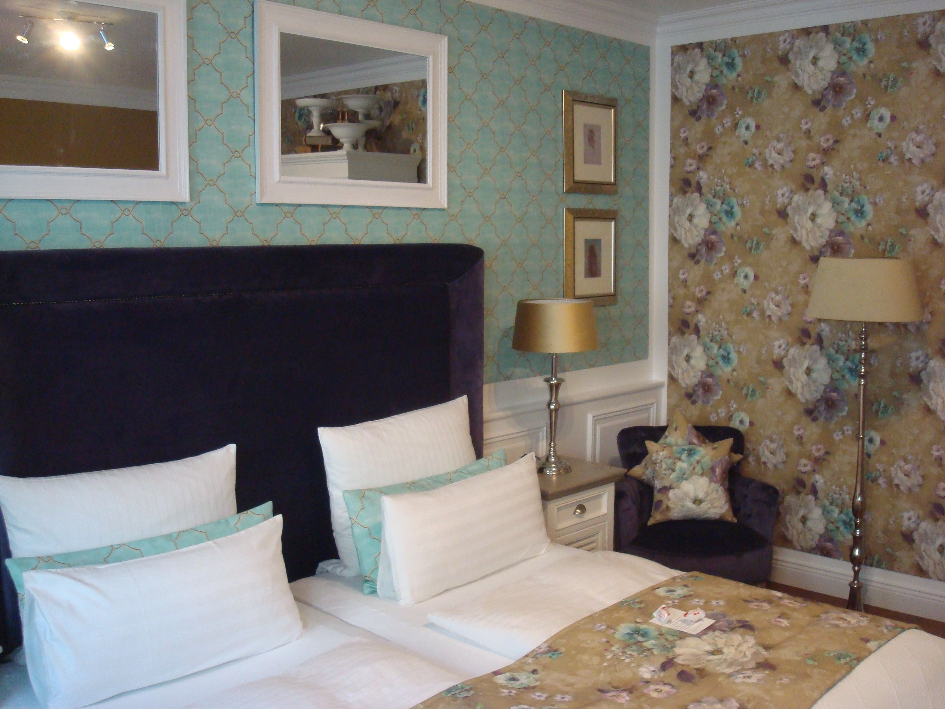 Een hotelkamer met een groot bed, twee nachtkastjes, een stoel en een spiegel.
