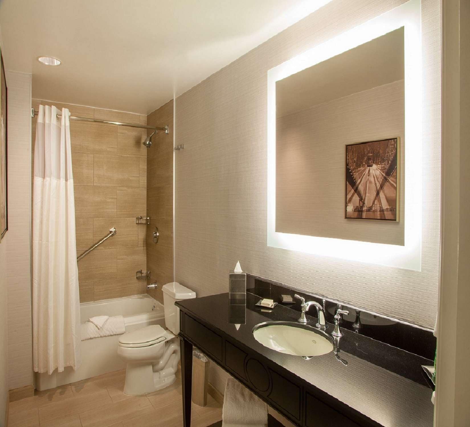 Un baño moderno con ducha, inodoro, lavabo y un espejo grande.