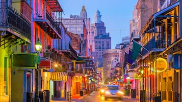 Calle histórica flanqueada por edificios, algunos con balcones y toldos, bajo un cielo crepuscular.