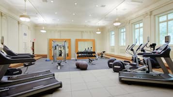 Une salle de sport spacieuse équipée de tapis de course, de ballons d’exercice et d’appareils de musculation.
