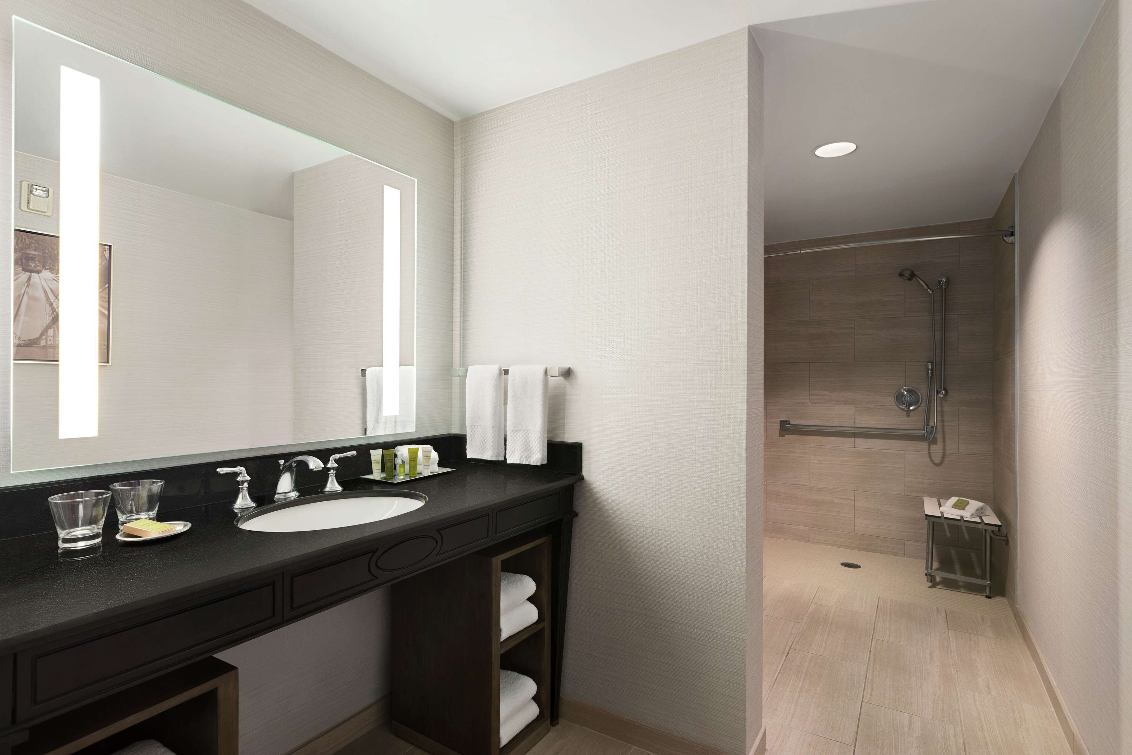 Un baño moderno con un espejo grande, un lavabo y una zona de ducha.