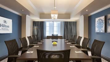 Une salle de conférence équipée d’une longue table, de chaises et d’un écran de projection.