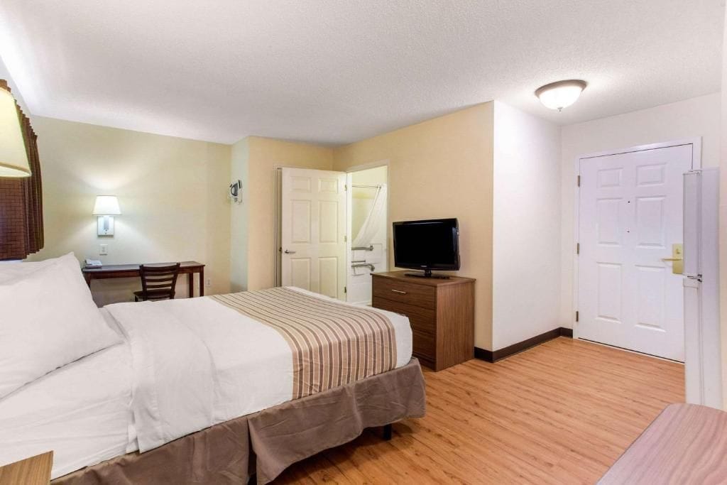 A hotel room with a bed, a desk, a television, and a wardrobe.
