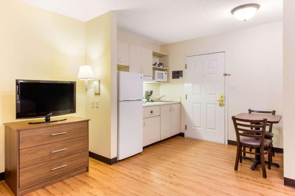 A compact kitchen with a microwave, refrigerator, and a dining area with a table and chairs.