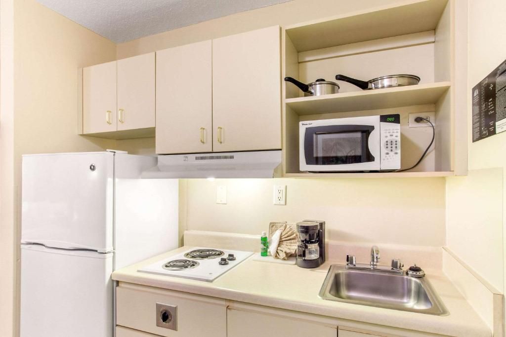 A compact kitchenette with a microwave, stove, sink, and a refrigerator.