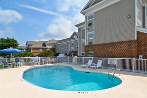 A swimming pool with a 5 ft depth, surrounded by a white fence, and adjacent to a building with brick and siding exteriors. - Studio 6 Extended Stay - Myrtle Beach, SC (Myrtle Beach)