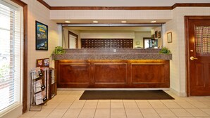 A reception area with a wooden reception desk, a bulletin board with flyers, and a door with a curtain. - Studio 6 Extended Stay - Myrtle Beach, SC (Myrtle Beach)