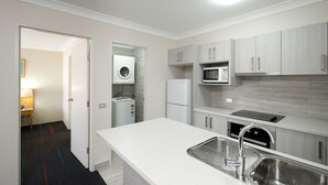 A modern kitchen with grey cabinets, a built-in microwave, a stainless steel sink, and a Samsung refrigerator. - APX Parramatta (Rosehill)