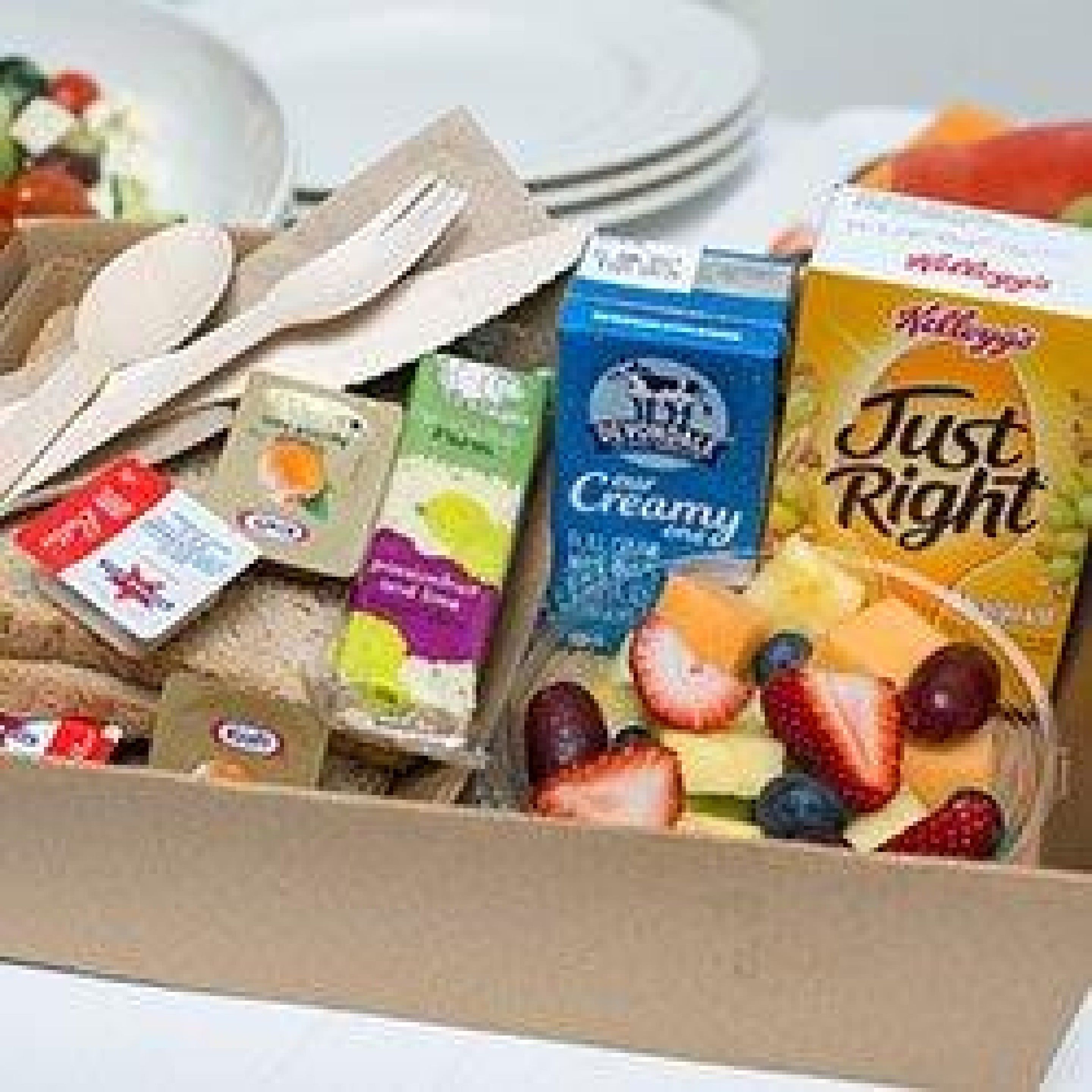 A box of assorted food items including yogurt, cereal, and fruit.