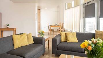 Una sala de estar moderna con dos sofás grises, una mesa de centro de madera y un comedor con una mesa y sillas de madera.