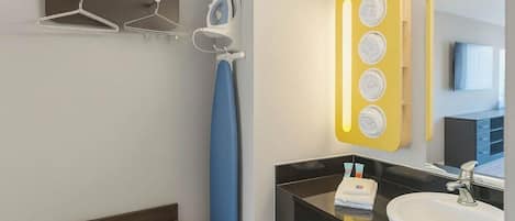 Un baño moderno con un lavabo negro, un espejo y un toallero amarillo.