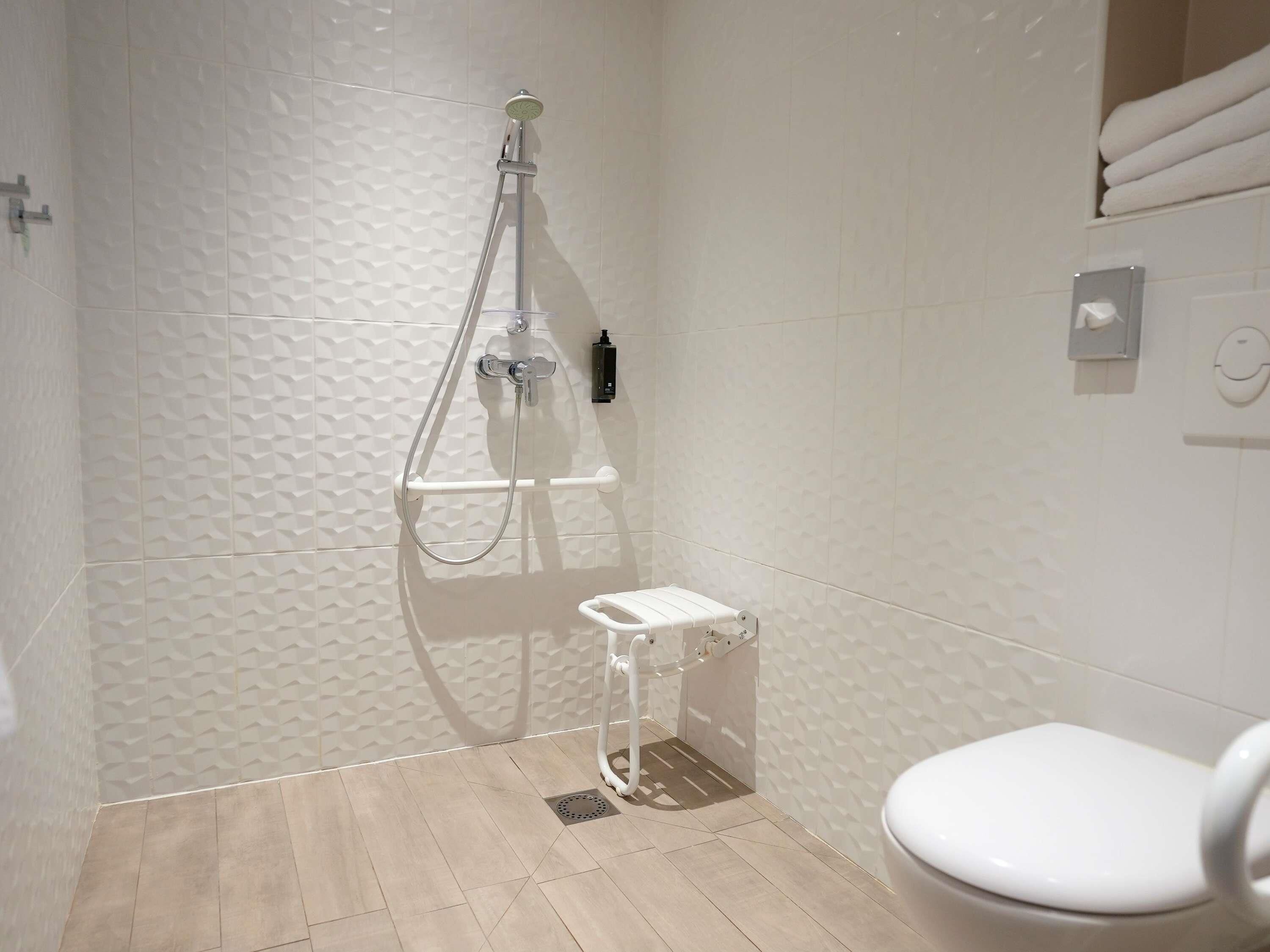 A bathroom with a shower, toilet, and a towel rack.