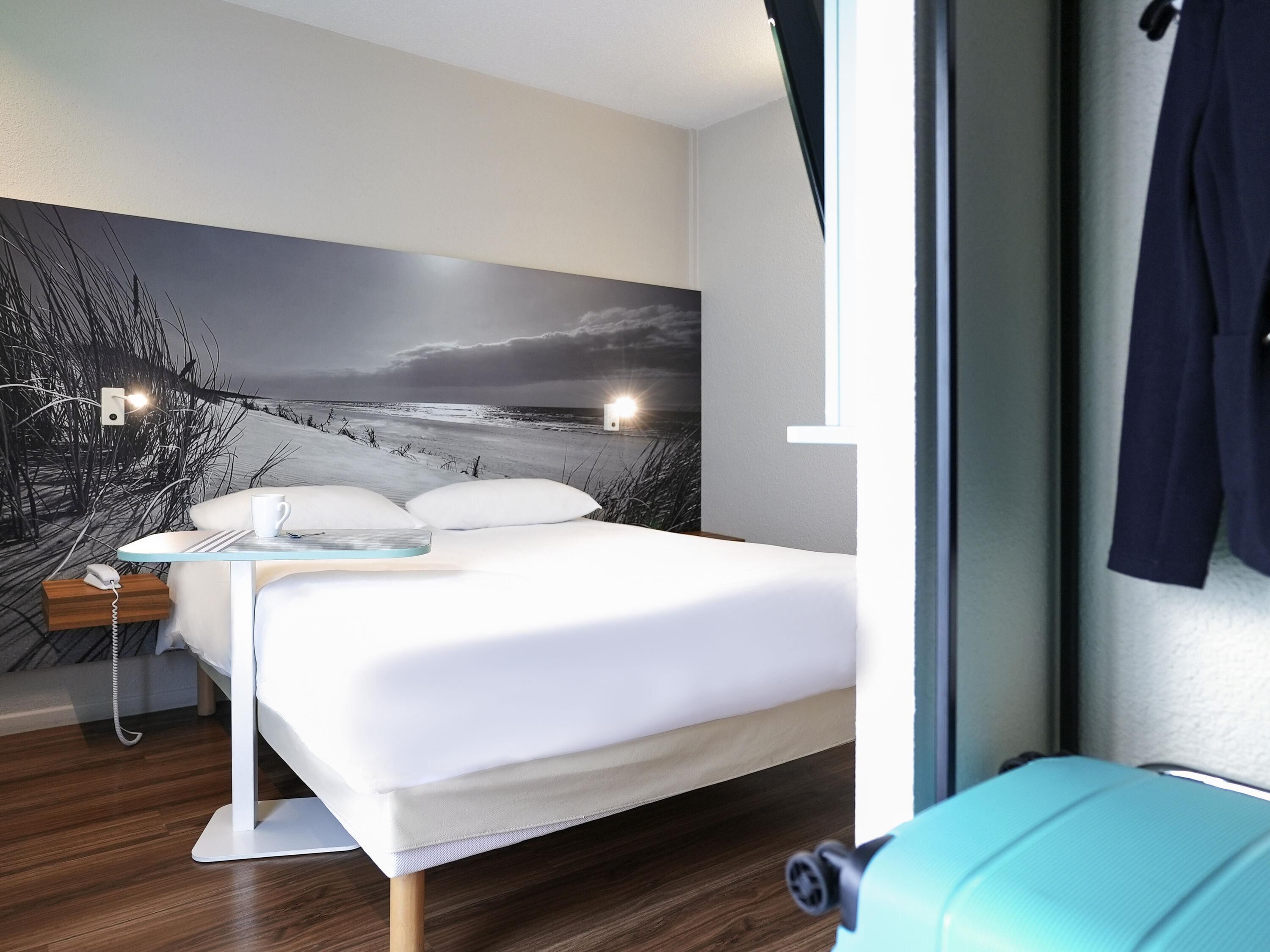 Quarto moderno com cama, mesa de cabeceira e lumin ária na parede.