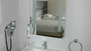 A hotel bathroom with a sink, mirror, and a towel rack.