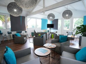 A modern living room with grey sofas, round coffee tables, and large windows. - ibis Styles Quimper (Quimper)