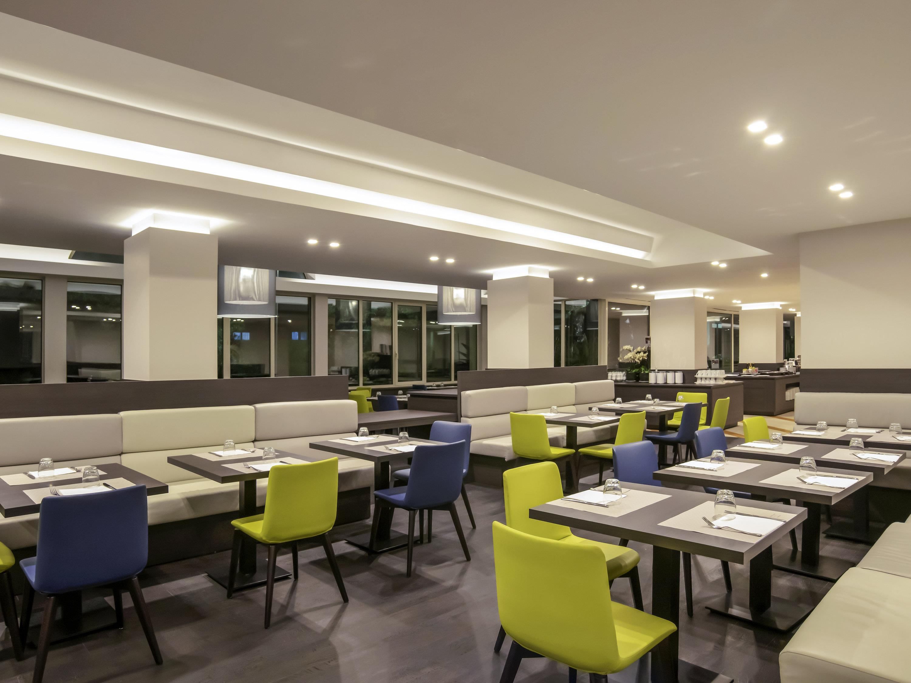 Un restaurante moderno con cabinas y mesas, iluminación colgante y vistas al exterior.