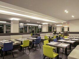 A modern restaurant with booths and tables, overhead lighting, and a view of the outside.