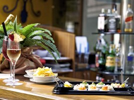 En bar med et cocktailglas, tallerkener med mad og en bakke med appetizers.