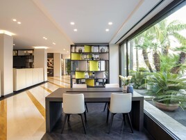 A modern kitchen with a dining area, featuring a large window with a view of palm trees.