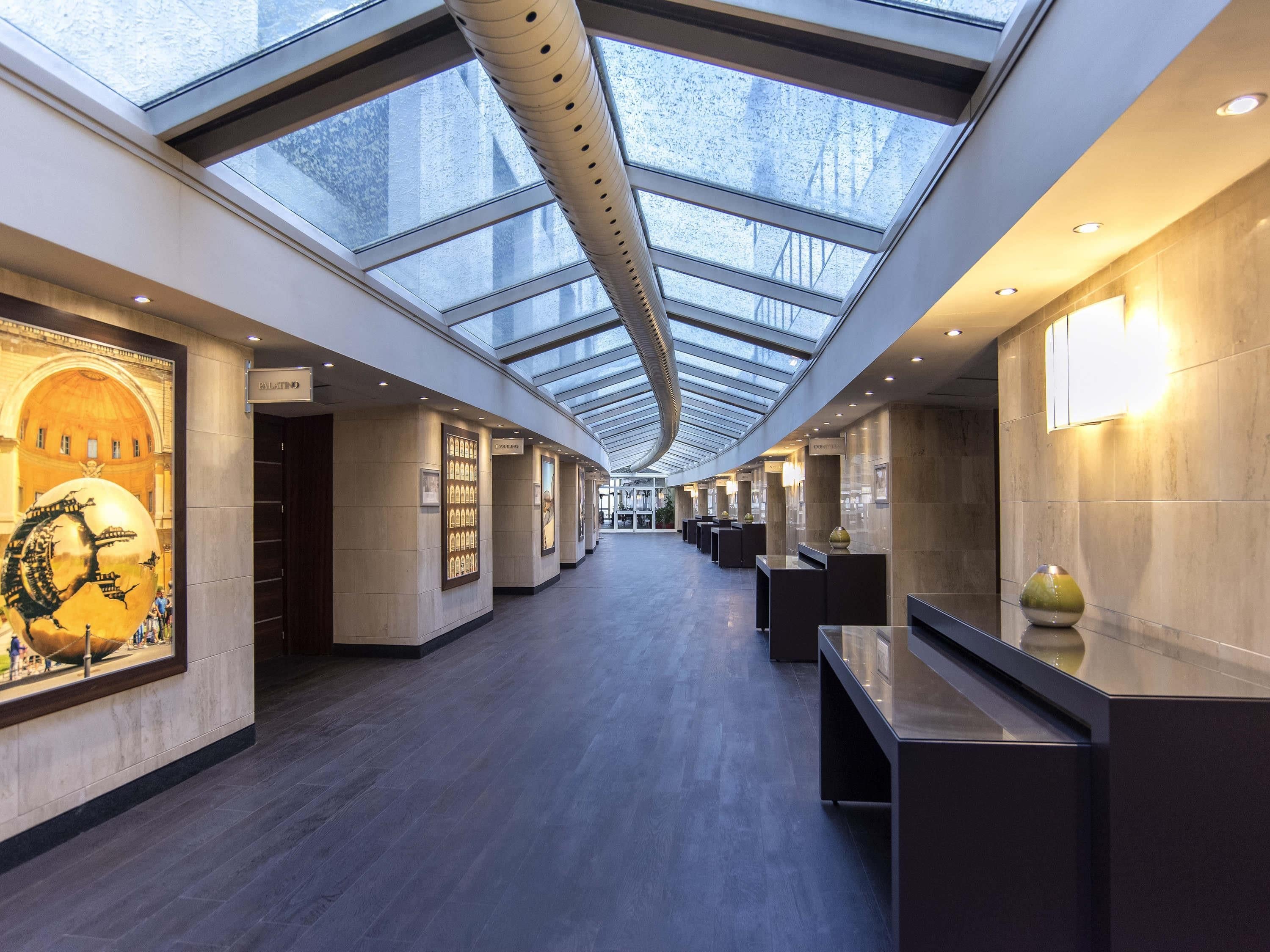 Een moderne hotelentree met een hoge plafond, dakramen en een centraal gelegen receptiebalie.
