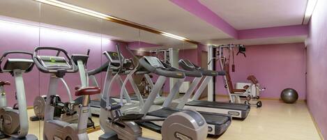Un gimnasio con cintas de correr, elípticas y una máquina de remo.