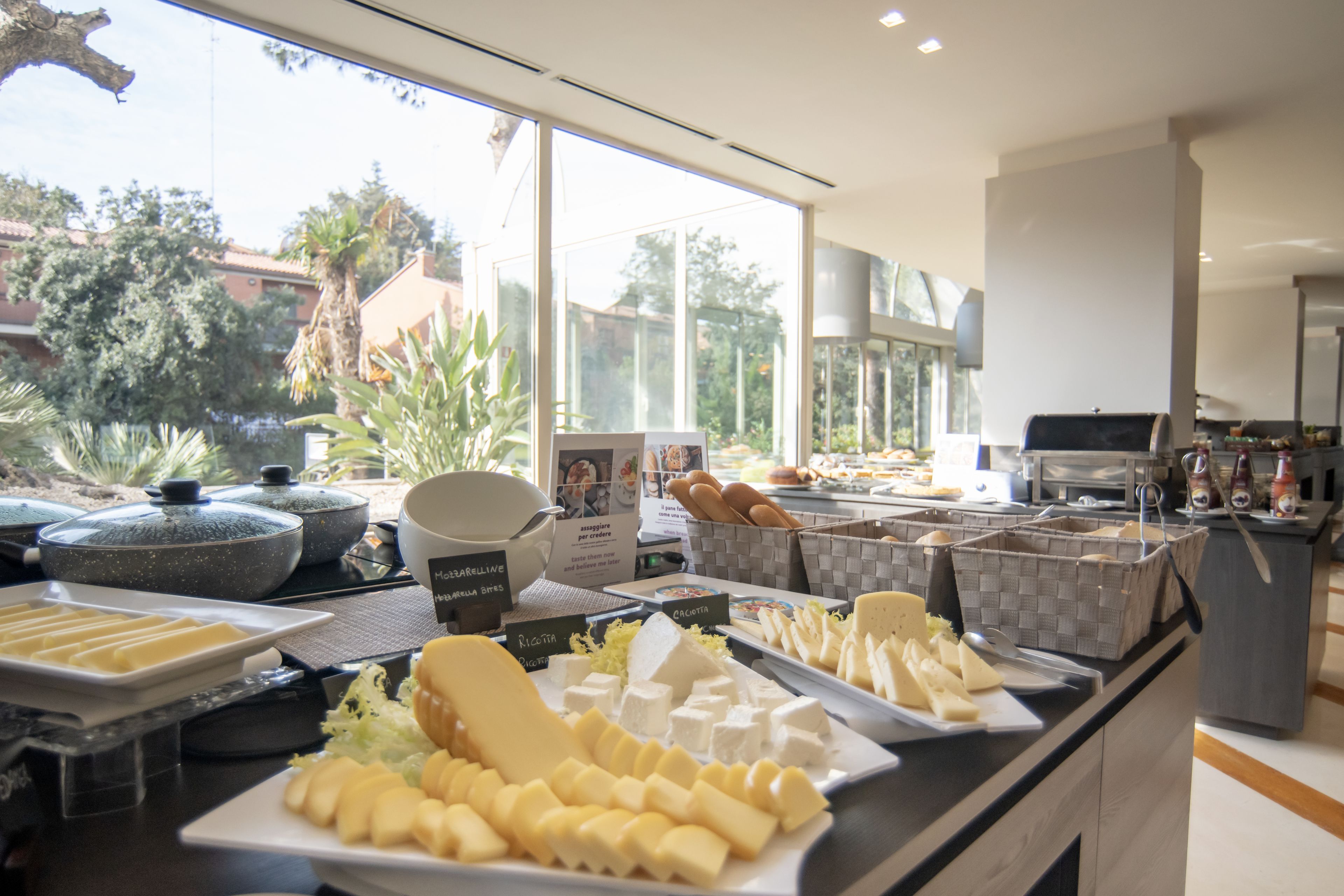 A buffet with various cheeses, breads, and other food items.