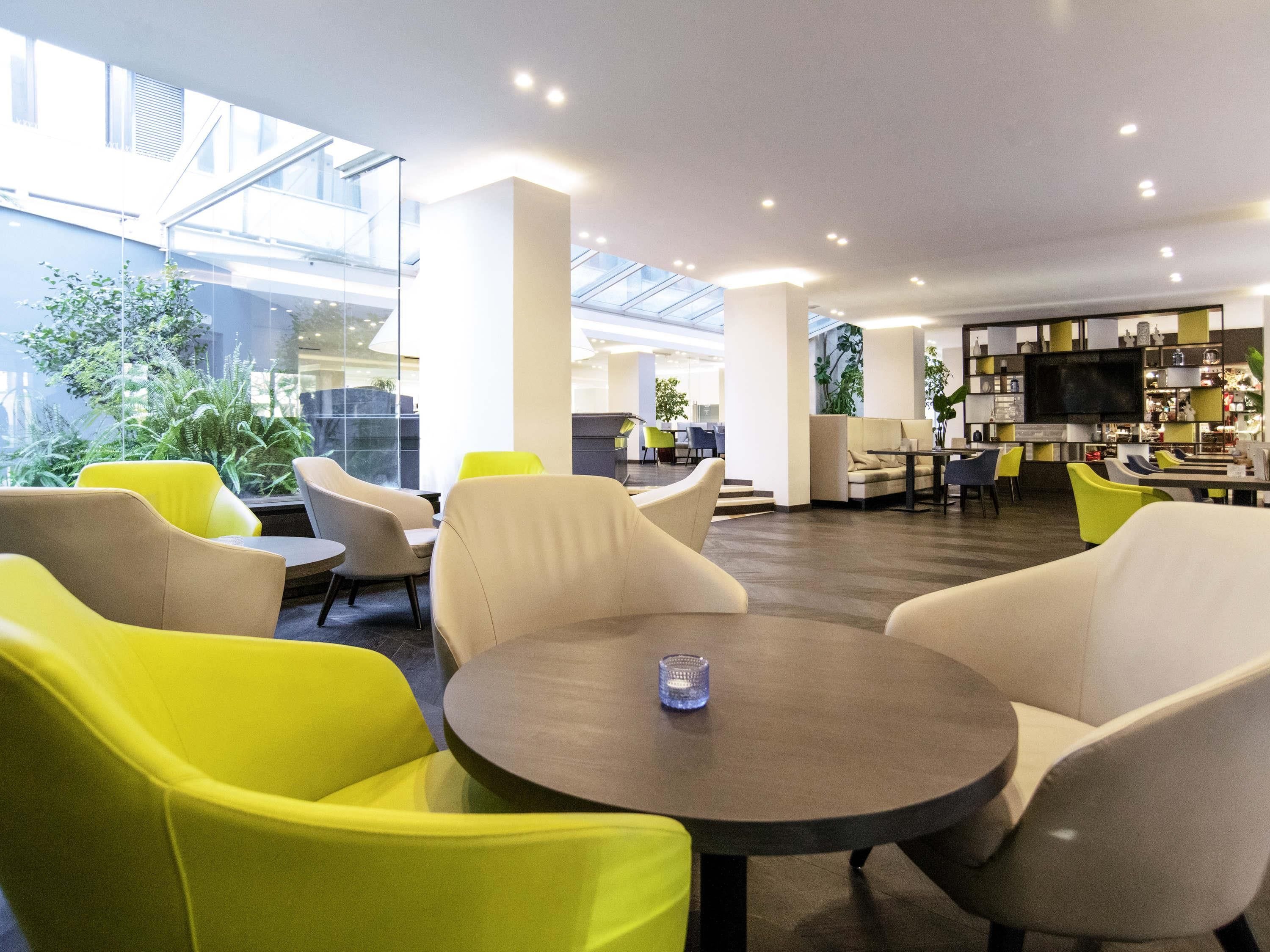 A modern indoor space with seating arrangements, a central table, and a bar area.