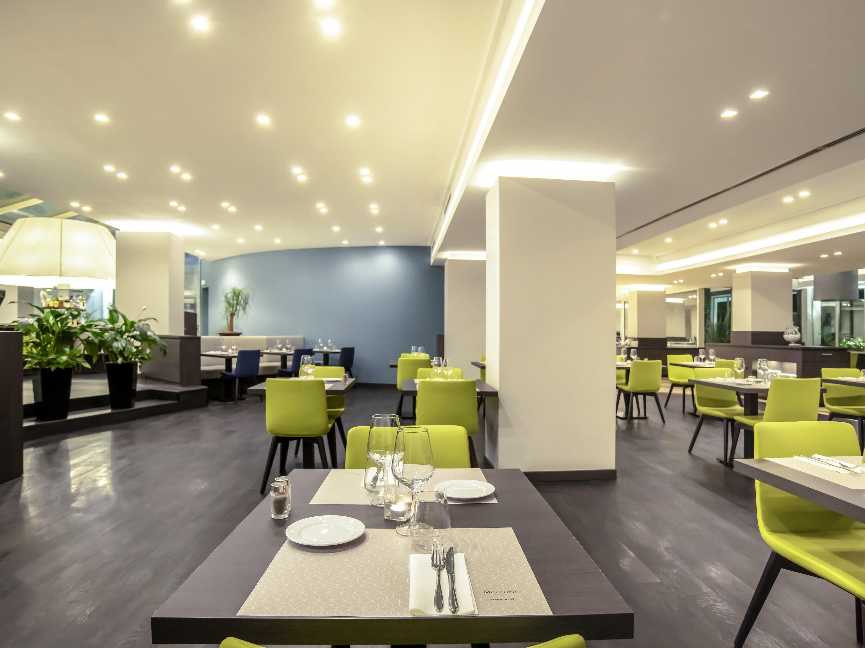 A modern dining area with tables set for two, featuring a neutral color palette and contemporary design.