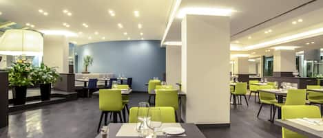 A modern dining area with tables set for two, featuring a neutral color palette and contemporary design.