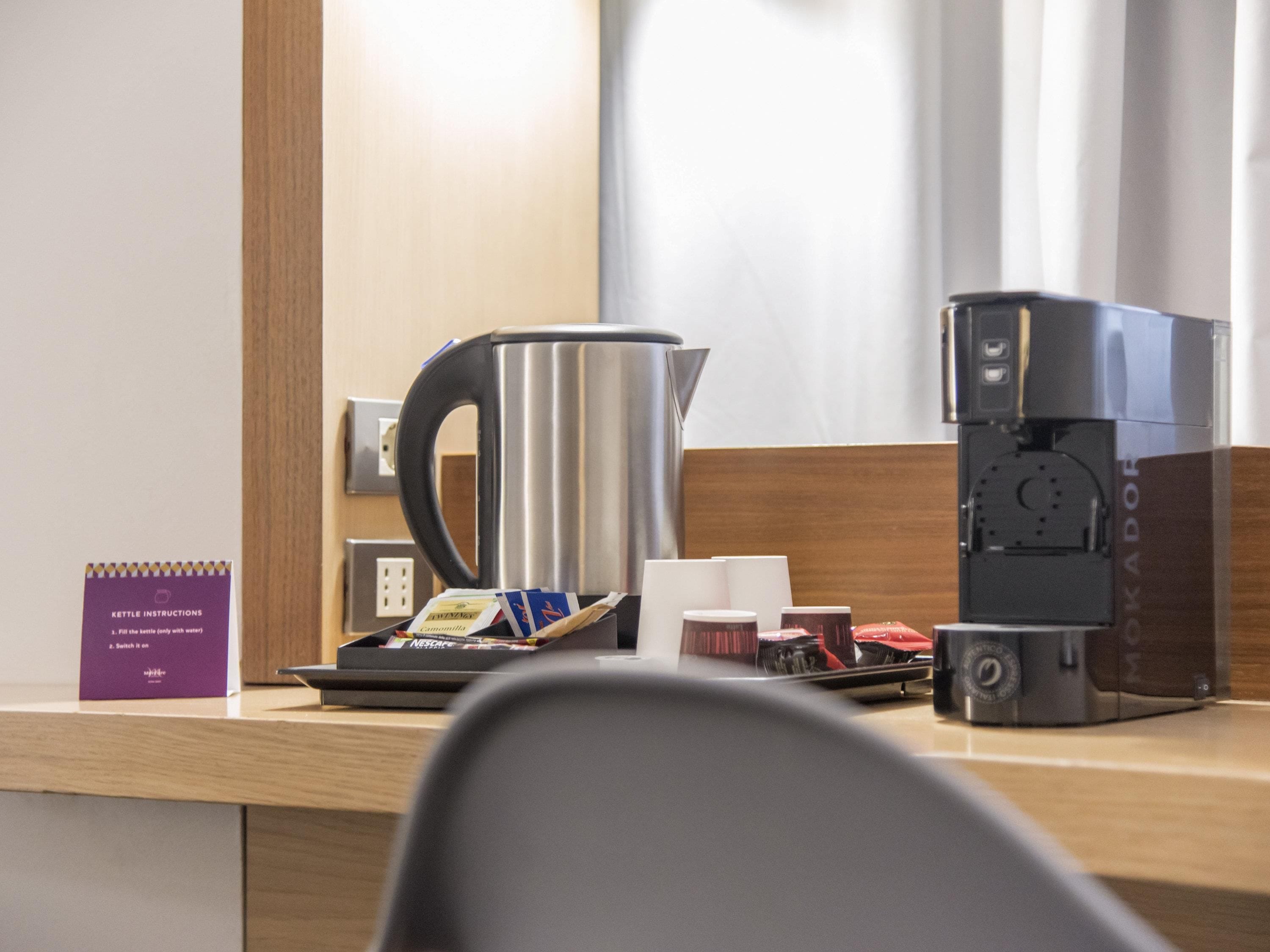 Habitación de hotel con cafetera, hervidor de agua y bloc de notas con instrucciones.