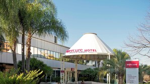 The exterior of Mercure Hotel with a modern design, including a covered entrance and a sign listing amenities like a congress center, fitness & spa, pool, restaurant, and lounge bar. - Mercure Eur Roma West (Rome)