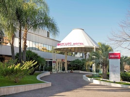 Eksteriørbillede af Mercure Hotel med et moderne design, inklusive en overdækket indgang og et skilt, der viser faciliteter som kongrescenter, fitness & spa, pool, restaurant og loungebar.