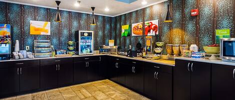 A modern kitchen with black cabinets, a tiled floor, and various food items and appliances.