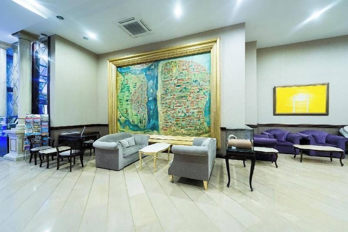 A lobby with a large map mural, seating area with sofas and tables, and a reception desk.