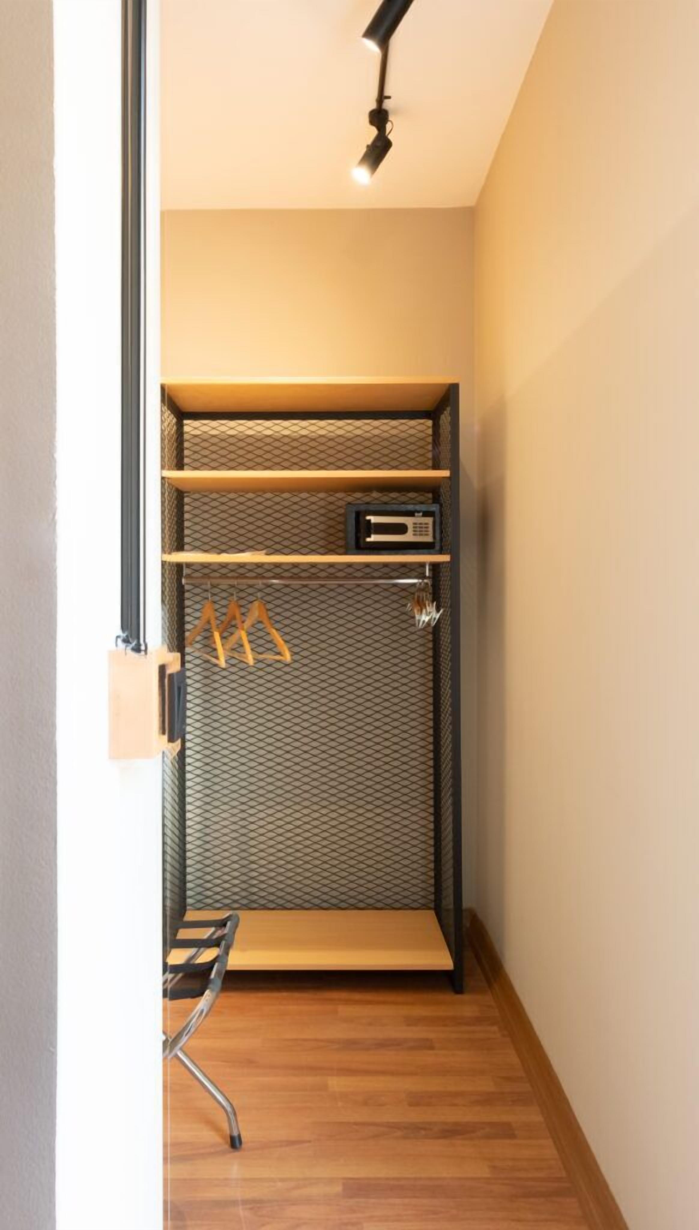 Un dressing accessible sans porte, doté d’une armoire à miroir, d’un four à micro-ondes et d’une tringle à vêtements.