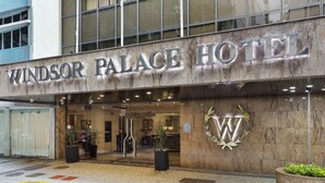 El exterior del Hotel Windsor Palace, con una entrada destacada, un logotipo grande y plantas en macetas.