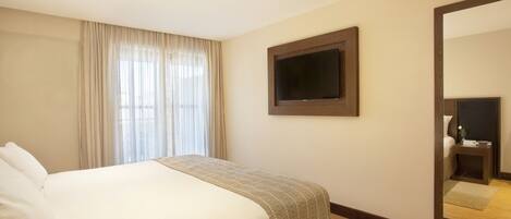 A hotel room with a bed, a television mounted on the wall, and a large mirror.