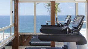 Un gimnasio con cintas de correr y vista al océano.