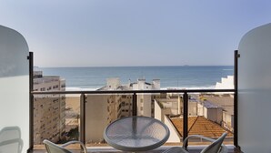 Un balcón con vistas al mar, una silla y una mesa.