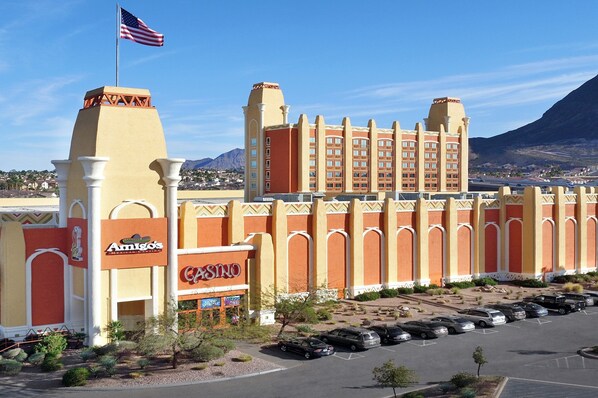 A large hotel with a casino, featuring a prominent American flag, a parking lot, and a mountainous backdrop. - Fiesta Henderson Hotel and Casino (Henderson)