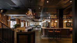 Un restaurant spacieux doté d’un bar central, de hauts plafonds et de murs en briques apparentes.