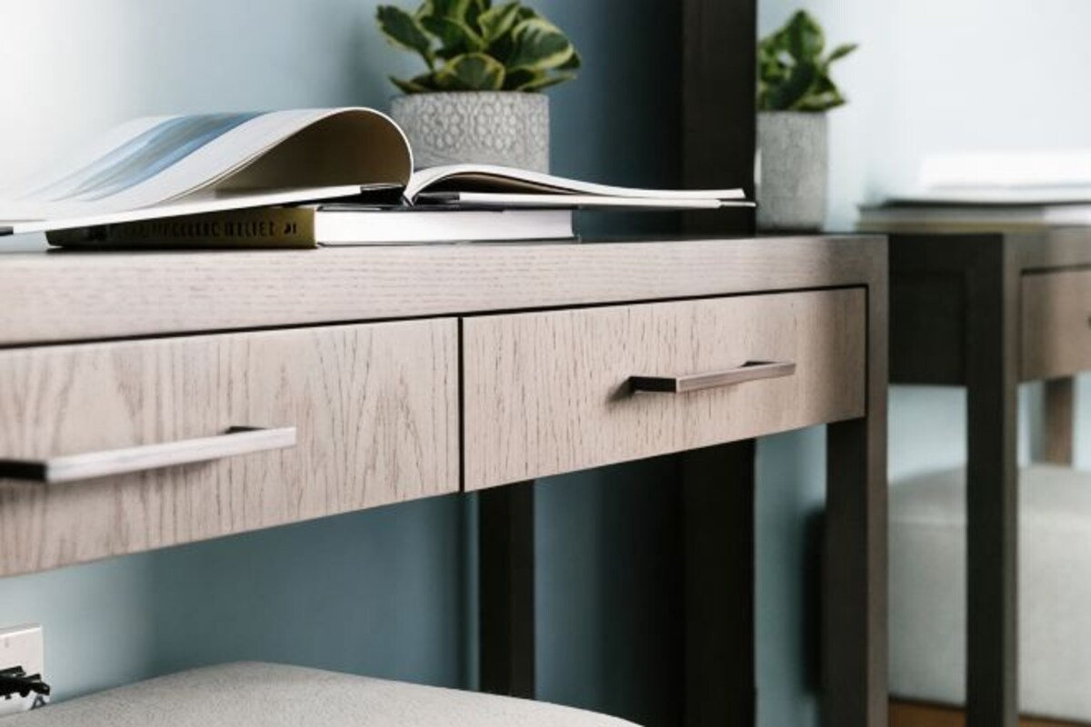 A modern desk with a book, a potted plant, and a drawer.