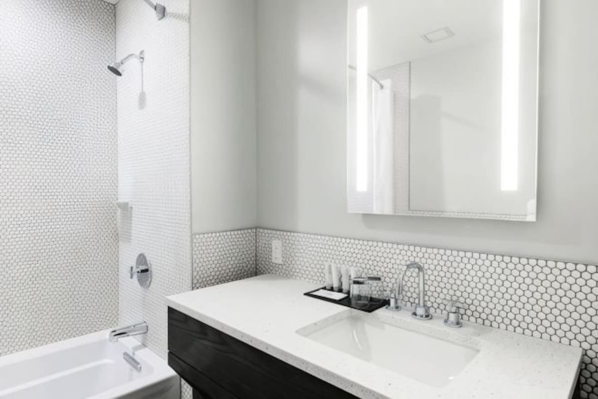 A modern bathroom with a white sink, mirror, and shower.