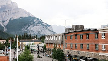 A town with a mountain backdrop, featuring a mix of brick and stone buildings, a central street, and a few pedestrians.